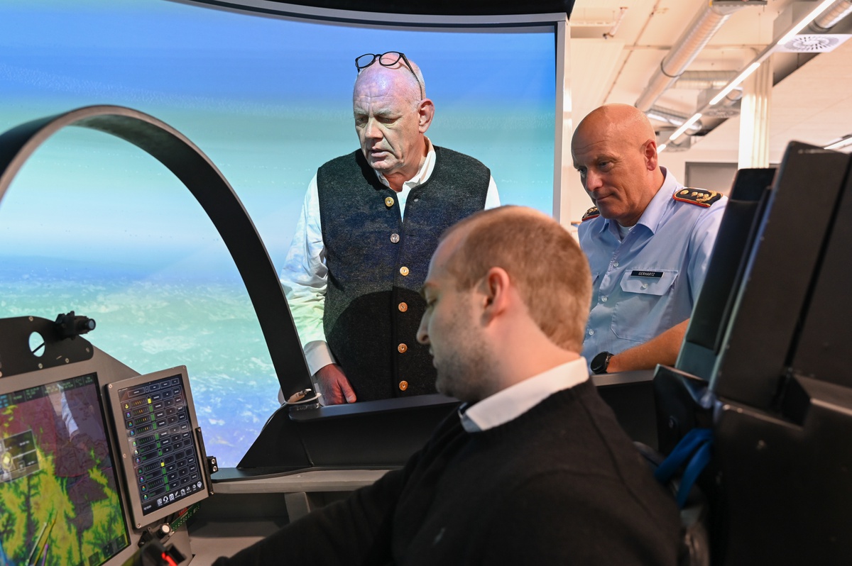 Prof. Schulte links und Generalleutnant Gerhartz rechts im Hintergrund lassen sich die Vorgänge im Flugsimulator von einem wissenschaftlichen Mitarbeiter erklären