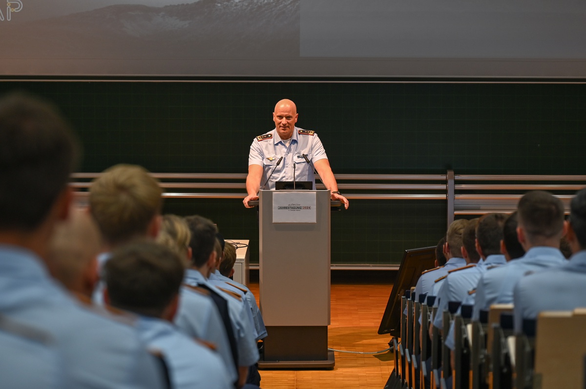 Aufnahme durch die Mittelreihe des mit Studierenden gefüllten Audimax. Vorne am Rednerpult spricht Generalleutnant Gerhartz.