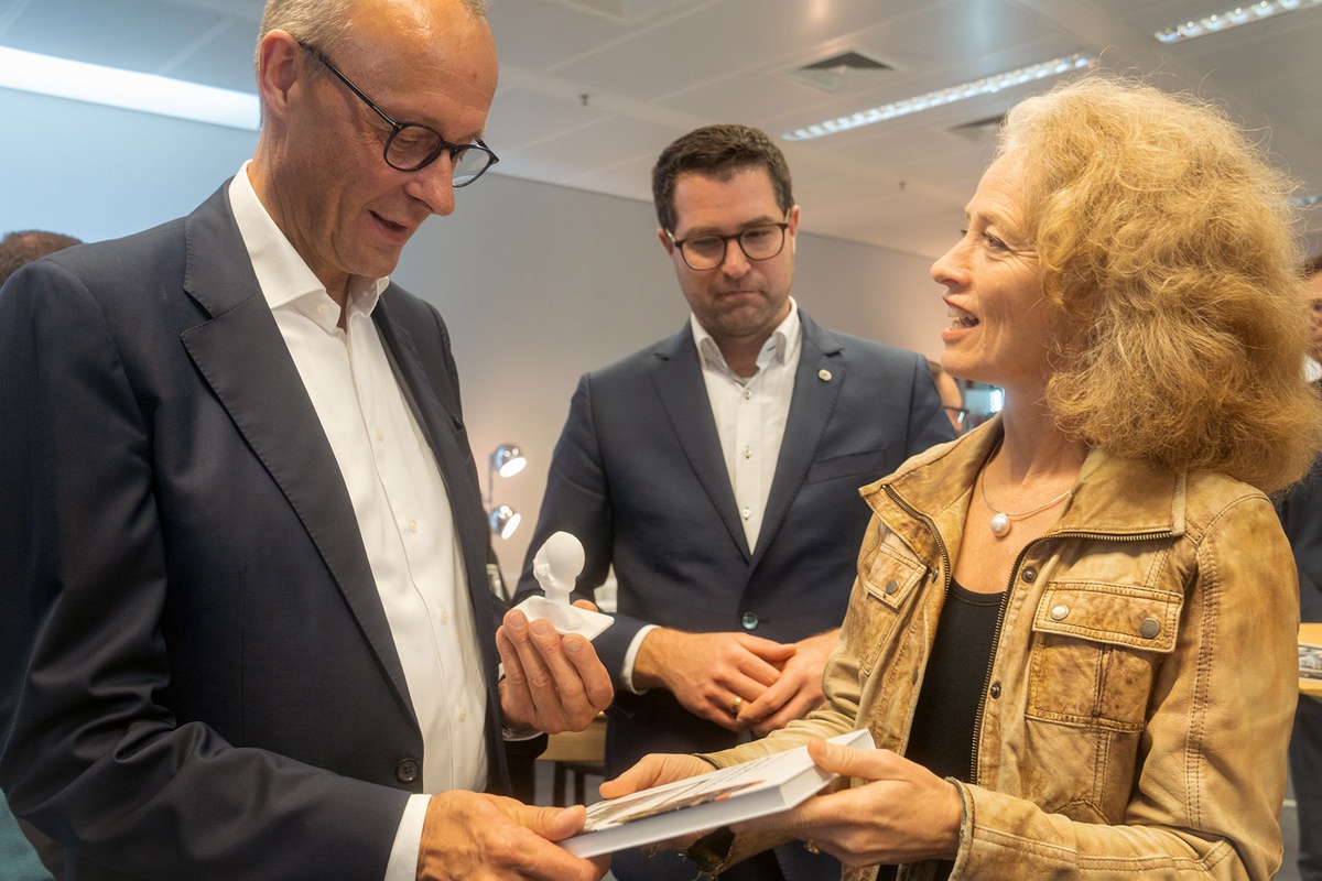 Links im Bild Friedrich Merz der auf die Statue der Athene blickt, die er in der Hand hält. Neben ihm, rechts im Bild, Prof. Kern, die ihm die Festschrift der Universität überreicht.